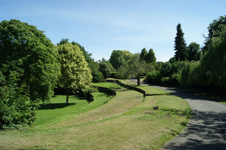 A path with trees all around it, and tiered levels on the left. 
